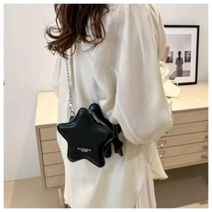 Sac bandoulière chic en forme d'étoile noire avec chaîne argentée sur tenue blanche