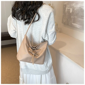 Detail of light beige ballet-style hobo bag with drawstring bow and pearl texture finish