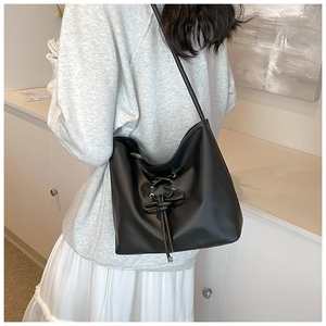 Detail of black ballet-style shoulder bag with lace-up drawstring design shown on model