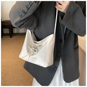 Close-up of cream ballet style bucket bag with bow tie detail and matte leather texture