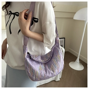 Detail of light purple quilted crossbody bag with colorful wavy embroidery and wide strap