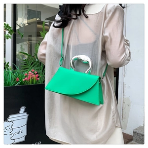 Detail of light luxury green geometric handbag with silver metallic handle on a shoulder strap