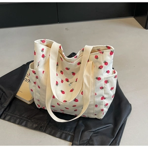 Close-up of strawberry print corduroy tote bag showing ribbed texture and side pocket