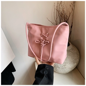 Detailed view of pink ballet style bucket bag with lace-up ribbon design and silver eyelets