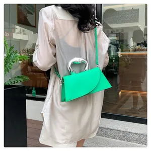 Detail of neon green crossbody bag with geometric flap and silver metal C-handle