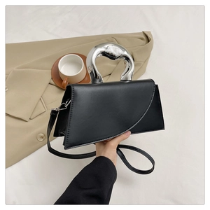 Detail of minimalist black bag with avant-garde silver liquid metal handle and flap