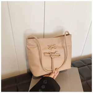Detail of beige ballet-style bucket bag with lace-up ribbon and bow design