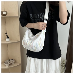 Detail of white quilted hobo bag featuring colorful vertical embroidery and wide strap