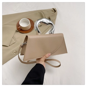 Detail of beige trapezoid handbag featuring a unique silver metallic organic handle