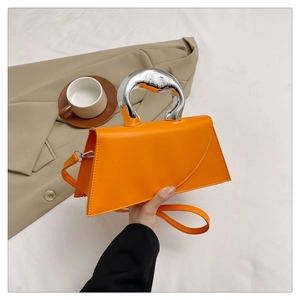 Detail of orange geometric handbag with a modern chrome silver metal handle and shoulder strap