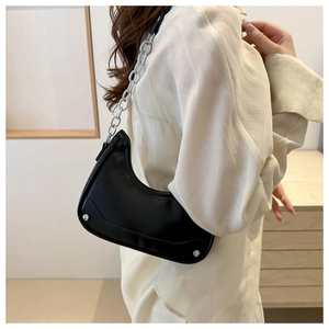Side view of a black leather crescent hobo bag with a chunky silver chain strap and rivets