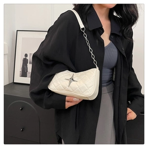 Detail of white quilted underarm bag with silver star metal accent and chain strap