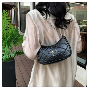 Detail of black quilted shoulder bag featuring silver star ornament and chunky metal chain
