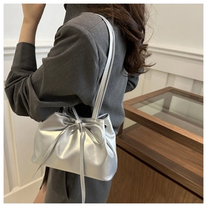 Detail of silver metallic drawstring bucket bag with bow accent and shiny finish