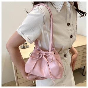 Detail of pink drawstring bucket bag with bow decoration and smooth PU leather finish