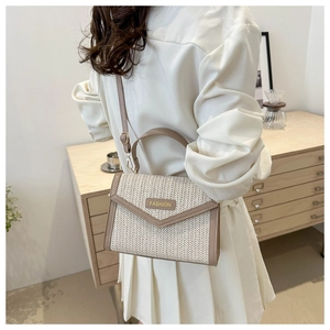 Détail du tissage et des finitions en cuir marron d'un sac bandoulière en paille chic