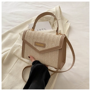 Détail du sac à main en paille tissée avec garniture en cuir brun et étiquette FASHION