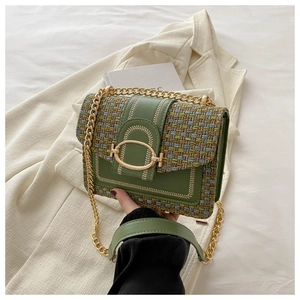 Detail van groene tweed crossbodytas met gouden ketting en ovale gesp op een blazer