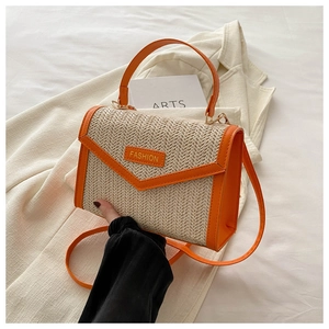 Détail du sac à main en paille tressée avec bordure en cuir orange et étiquette