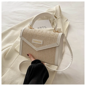 Détail du sac à main en paille tressée avec bordure en similicuir blanc et lettrage