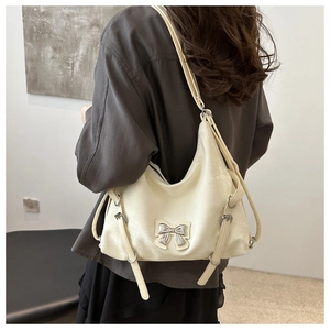 Détail du sac à bandoulière crème avec nœud en métal argenté et accessoires punk