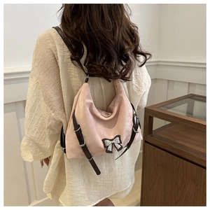 Modèle portant un sac hobo rose en daim avec bretelles marron dans une pièce chaleureuse