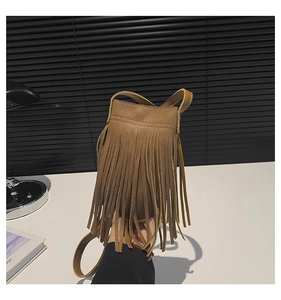Detailed view of a brown leather bucket bag with long fringe tassels and a slim shoulder strap