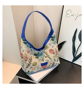 Close-up of floral tapestry fabric and royal blue leather strap on tote bag