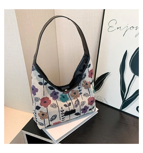 Detail of floral jacquard texture and black leather strap on a retro tote bag