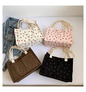 Detail of four corduroy tote bags with strawberry prints and double front pockets