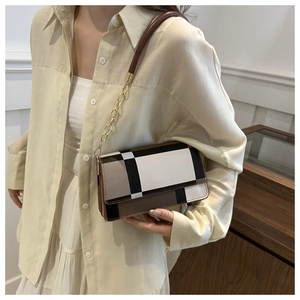 Detail view of the geometric check pattern on the crossbody flap bag with gold chain strap
