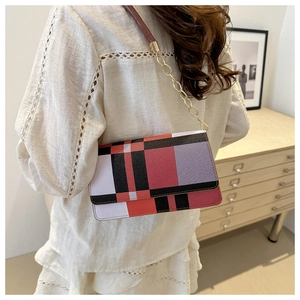 Detail of color-block geometric shoulder bag with gold chain strap in a lifestyle setting
