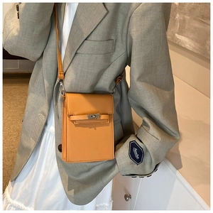 Détail d'un mini sac carré orange avec fermoir rotatif argenté et fine bandoulière