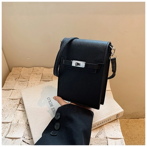 Détail macro du sac bandoulière en cuir Saffiano noir avec fermoir tournant argenté