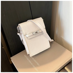 Détail d'un sac bandoulière blanc crème avec fermoir rotatif argenté sur fond bois