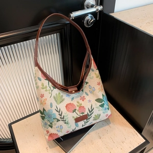 Floral embroidery hobo tote bag with brown leather strap on stone surface