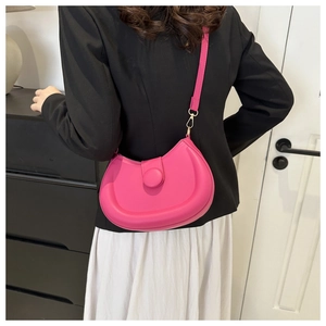 Detail of rose red half-moon shoulder bag with smooth texture and gold metal hardware