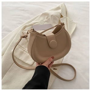 Detail of beige crescent moon bag with matte leather finish and large decorative buckle