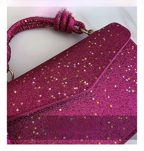Detail of rose pink glitter handbag featuring gold star sequins and woven handle texture