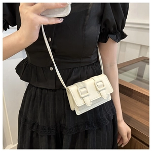 Mini cremefarbene quadratische Umhängetasche getragen zu einem schwarzen Kleid für Damen