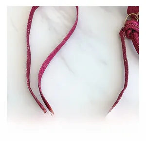 Close-up of sparkling rose red sequined shoulder strap with golden metal buckle