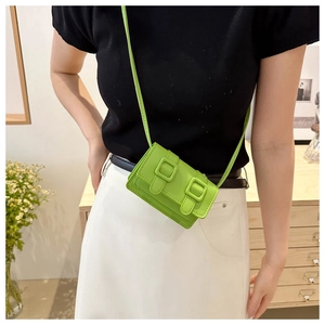Detailansicht der hellgrünen Mini-Umhängetasche mit Schnallen auf einem Model-Outfit