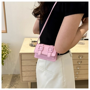 Detailansicht der rosa Mini-Umhängetasche mit Doppel-Schnallenriemen und feiner Lederstruktur