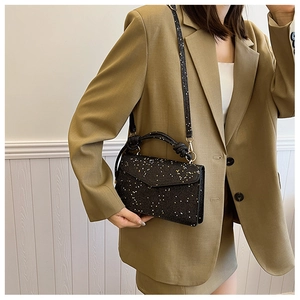 Close-up of black sequined handbag with gold hardware and fine glitter texture details