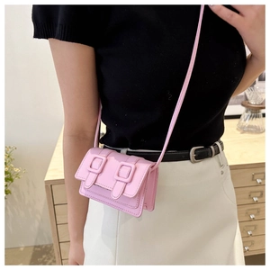 Nahaufnahme einer rosa Mini-Umhängetasche mit doppelten Schnallen auf der Klappe