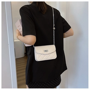 Détail du sac matelassé blanc avec chaîne argentée, boucle et bille de réglage métal