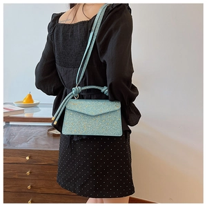 Detail of light blue glitter crossbody bag with a knot handle and sparkling texture