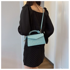 Close-up of light blue sequined crossbody bag with gold accents on female model