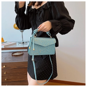 Close-up of a light blue sequin handbag with a unique knotted handle and glittery texture