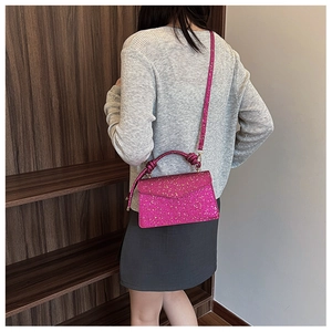 Pink sequin crossbody bag with twisted handle and envelope flap shown on model